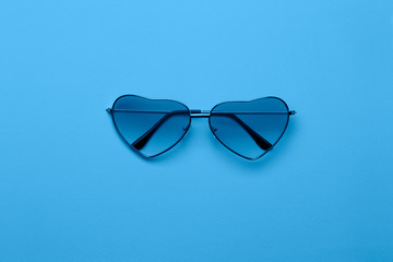 Bright blue heart-shaped glasses on a paper background.