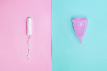 Tampon and silicone cup on different colored bacgkround, top view