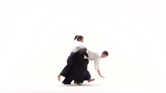 Man and woman in white keikogi showing aikido techniques, isolated on white. Slow motion.