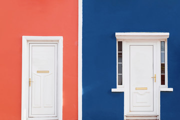 Facade colored in coral and mint colors with two white doors.