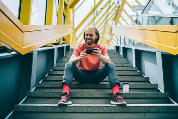 Laughing man with phone on steps of pedestrian bridge