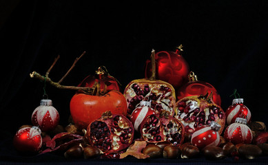 christmas balls among pomegranates and autumn fruits in black background