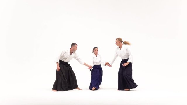Two males and female demonstrating aikido techniques, isolated on white. Slow motion.