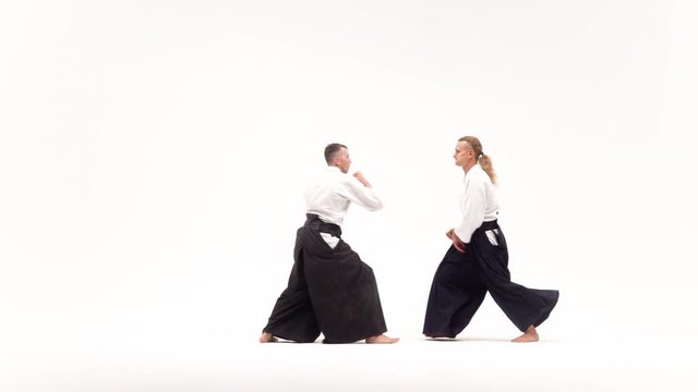 Two men in kimono practicing aikido techniques, isolated on white. Slow motion.