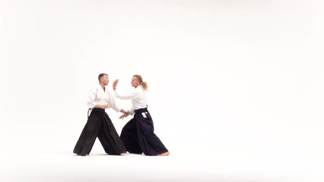 Two men in kimono practicing aikido techniques, isolated on white. Slow motion.
