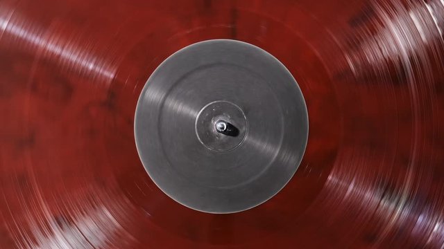 Red vinyl background with a grey screen in center. The vinyl record on DJ turntable record player close up. The rotating plate and stylus with the needle close-up. Loop. Macro. View above