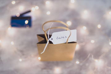 marketing and purchases concept, shopping bags from topdown perspective with payment cards and price tag surrounded by fairy lights bokeh