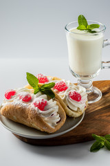 Kefir is decorated with a leaf of mint, a fermented drink. Air cake on a saucer on a white background