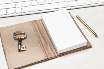 High key feminine workspace with pad, pen and computer keyboard, and old fashioned key.