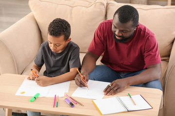 Portrait of African-American man and his little son drawing at home