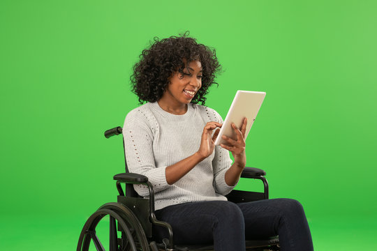 Happy disabled black woman using tablet on greenscreen