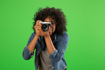 Portrait of happy black female photographer taking a photo on greenscreen - obrazy, fototapety, plakaty