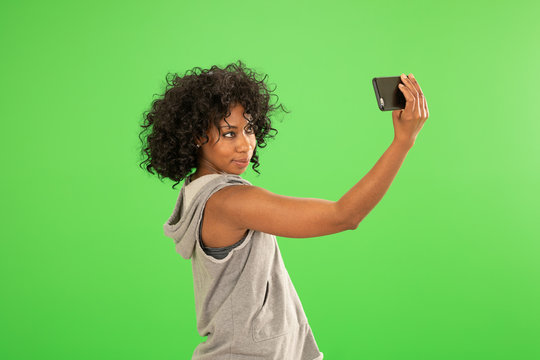 Young pretty African woman taking a selfie with cellphone on greenscreen