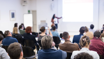 Business and entrepreneurship symposium. Female speaker giving a talk at business meeting. Audience...