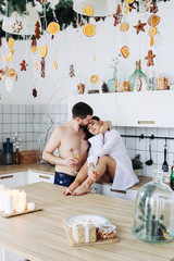 couple in the kitchen with christmas decoration, kiss each other, new year