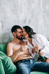 couple celebrating new year, green sofa, laughing, sparkling wine