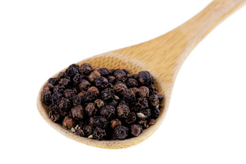 Spoon full of black peppercorns on a white background