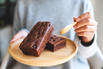 Closeup image of a woman eating delicious brownie cake with spoon