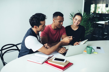 Cheerful coworkers working with laptop in office