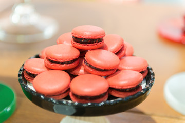 Red Macarons. Several strawberries-flavored pink macarons on a white and black ceramic tray. Children's party decoration with the detective theme. Selective focus with blur.