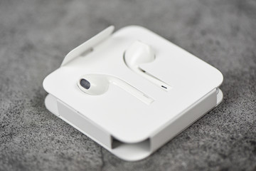 White wireless bluetooth earphones or headphones smartphone Earphones in plastic storage case isolated on gary