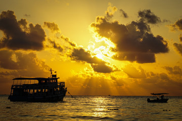 Fishing boat trawler and fisherman on the water ocean and dramatic clouds sky at sunrise - fishing...