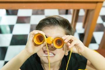 Top view of child looking through toy yellow binoculars on . Close up photo with focus on the...