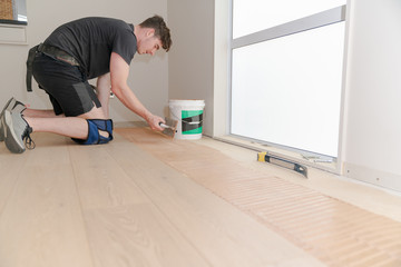 Tradesmaen laying new wooden floor in home.