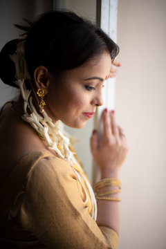 Portrait of an young and attractive Indian  woman in white traditional wear getting ready for the celebration of Onam/Pongal in white background. Indian lifestyle.