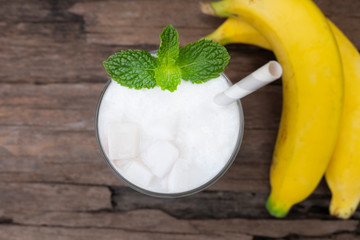 Coconut blend banana milk smoothie drink fresh cocktail shake milkshake vanilla juice fruit beverage food healthy the taste yummy In glass on wooden background from top view.