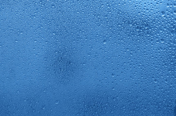 Window with water drops. Blue colored trendy background.