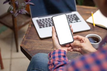 Mockup image blank white screen cell phone.men hand holding texting using mobile on desk at home office. background empty space for advertise text.people contact marketing business and technology 