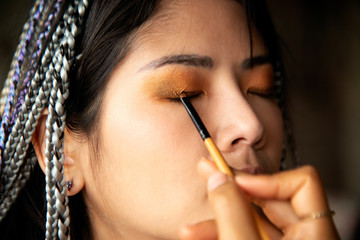 Makeup artist writing eyes for an Asian woman.