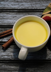 Turmeric latte, golden milk or the anti-inflammatory Indian Haldi Doodh with superfood Turmeric powder, Ginder and Cinnamon sweetened with honey on wooden background
