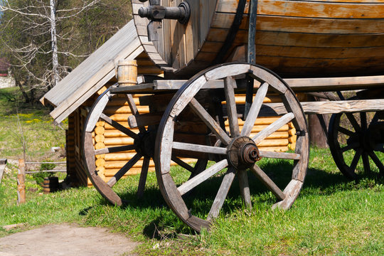 A close-up of two wheels of an antique trolley for the carriage of goods in a large barrel. Wooden barrel for beer, wine or drinking water.
