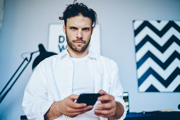 Obraz na płótnie Canvas Serious man texting on cellphone in creative studio