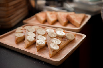 french toast with bananas on wood dish
