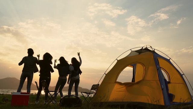 Group of teenage asian girl dancing and party with drink bottles happy enjoy travel camping beside the lake at sunset. Camping concept