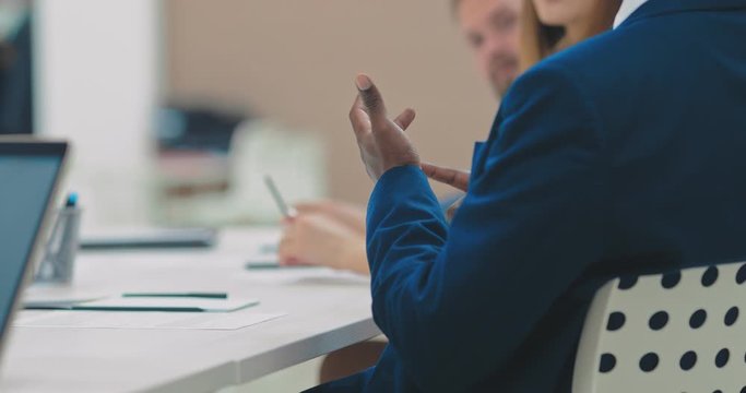 Black employee gestures at a meeting, business office. Hands, close-up.