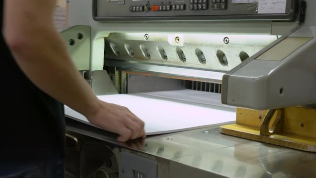 Man cutting paper with big paper cutter machine
