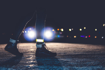 girl crosses the road at night. reflective bracelet. winter road safety concept.