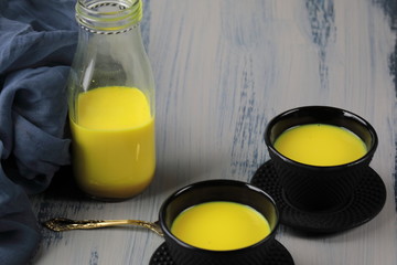 Turmeric latte, golden milk or the anti-inflammatory Indian Haldi Doodh with superfood Turmeric powder, Ginder and Cinnamon sweetened with honey on wooden background