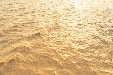 Abstract photo of surface water of sea or ocean at sunset time with golden light tone.