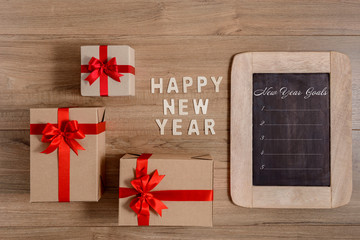 HAPPY NEW YEAR 2020 Wood and New Year's Goals List written on chalkboard with gift box