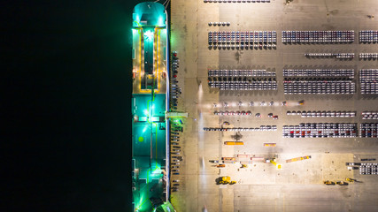 Aerial top view car carrier vessel at night, rows of new cars at night waiting to be dispatch and...