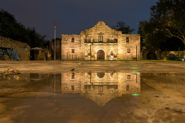Low Angle View of the San Antonio Alamo Reflected on Rain Puddle - obrazy, fototapety, plakaty