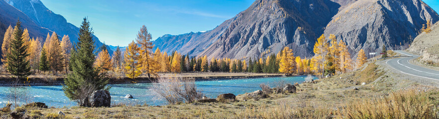 Scenic panoramic view. The road goes along a mountain gorge along the river. Rocks and autumn forest. Chuysky tract in the mountains of Altai, Russia.