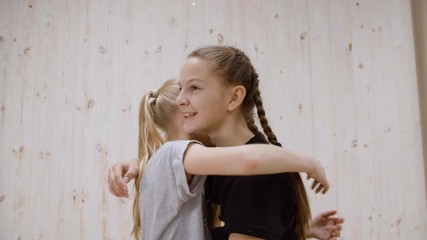 Happy girl friends hugging on meeting on light studio background. Two girl teenager embracing while friendly meet