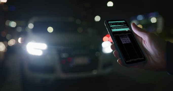 Close up of a businessman is using a futuristic application of self pilot with augmented reality holograms in a smartphone before a drive a car.