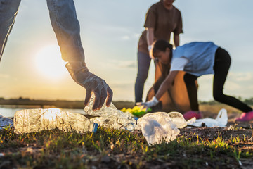 Naklejka na ściany i meble people volunteer keeping garbage plastic bottle into black bag at park near river in sunset